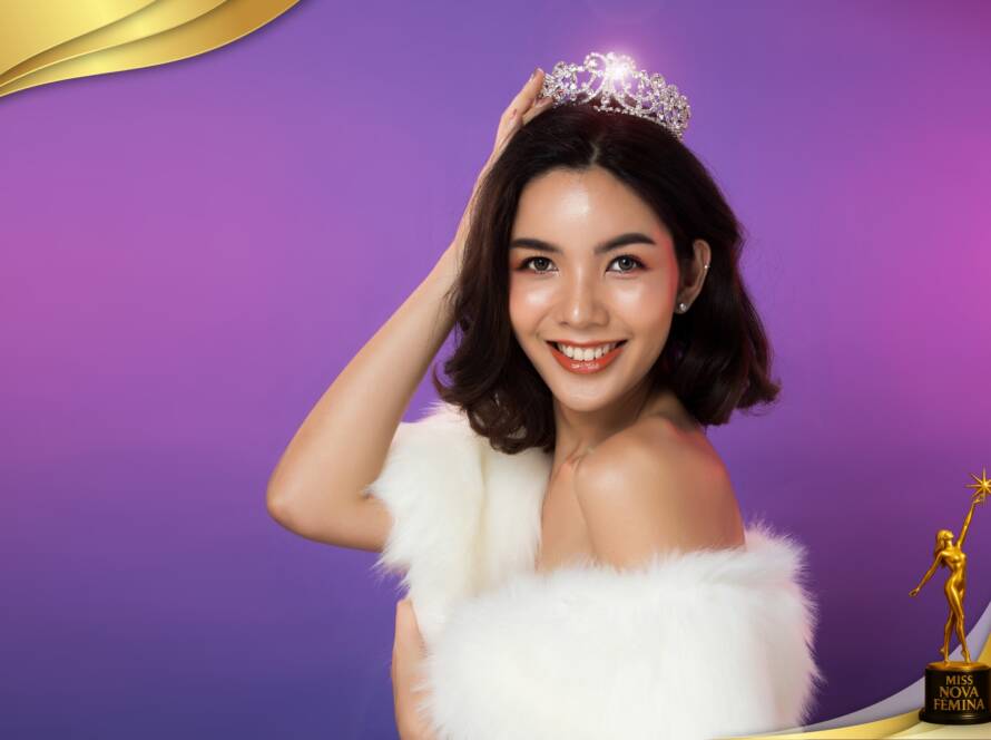 Concursante de Miss Nova Fémina Miami 2025 sonríe mientras coloca una corona sobre su cabeza, vistiendo un estola blanca sobre fondo violeta.