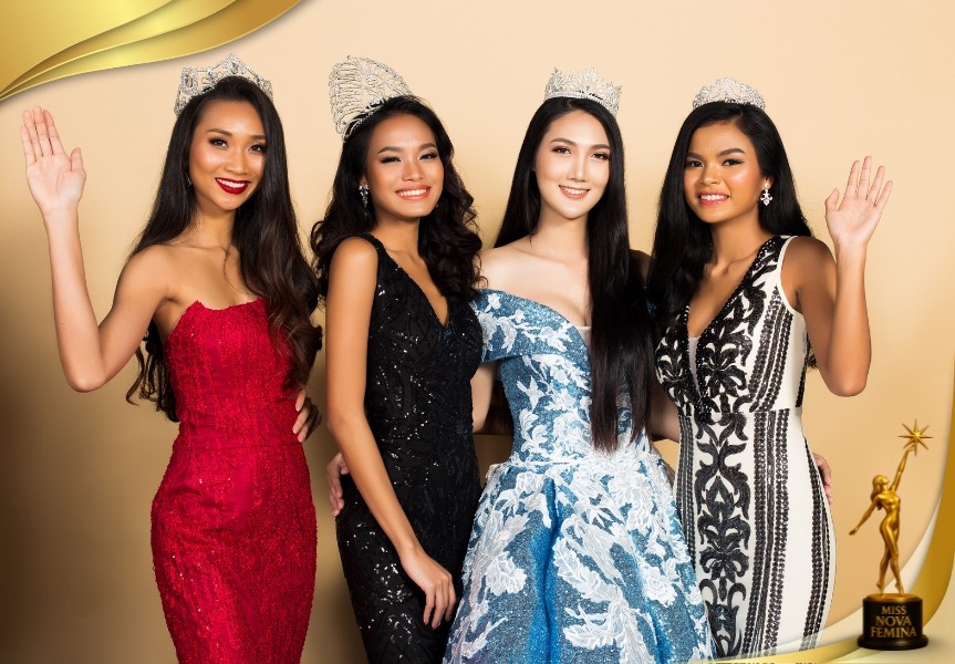 Four Miss Nova Fémina contestants wearing crowns and glamorous gowns, smiling and posing together on stage.