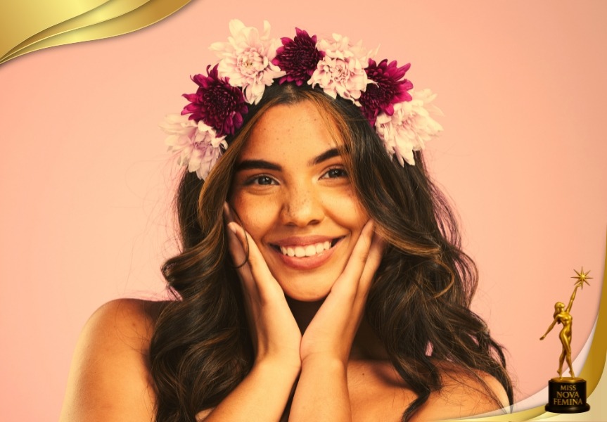 Retrato artístico de una mujer con una corona de flores, sonriendo frente a un fondo rosado, representando la alegría, la pureza y la esencia natural de la feminidad en Miss Nova Fémina.