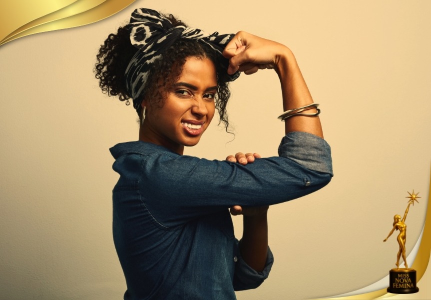 Retrato conceptual de una mujer levantando el brazo en señal de fuerza y empoderamiento, vestida con camisa de mezclilla y pañuelo en el cabello, representando la independencia y el espíritu de Miss Nova Fémina.