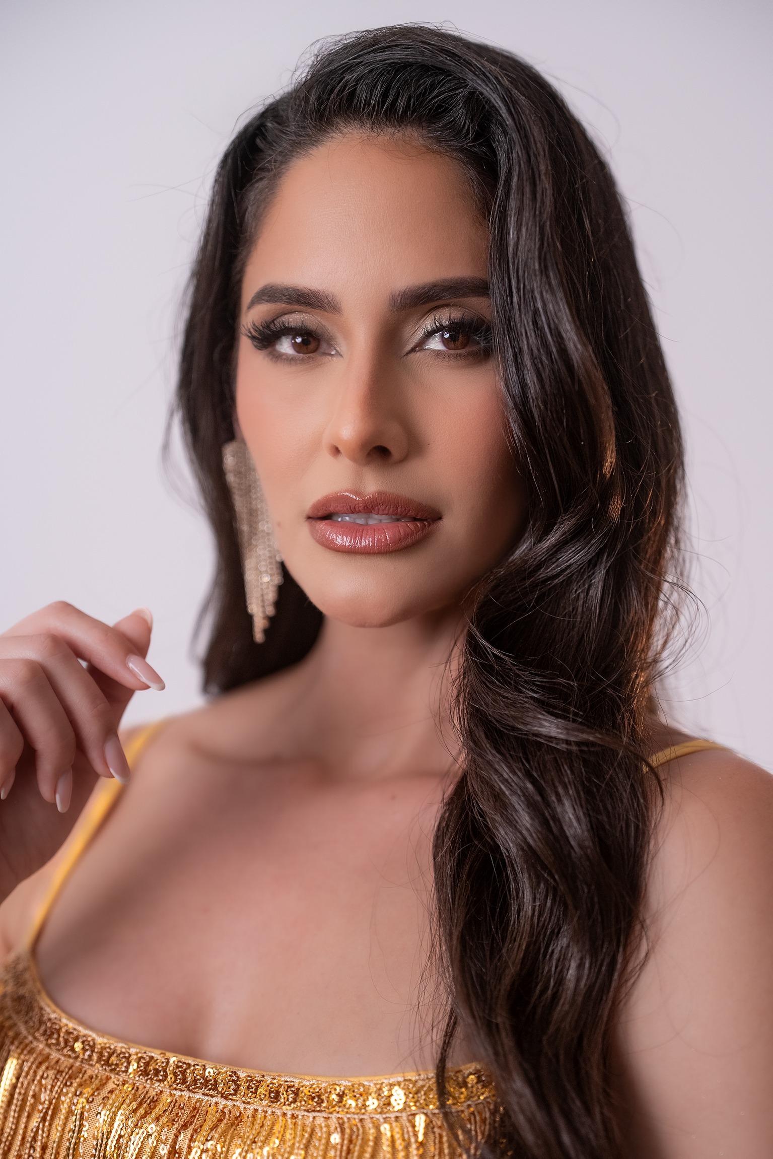 Retrato de Liusbetty Hernández Valdés, concursante número 29 de Miss Nova Fémina, con vestido dorado elegante.