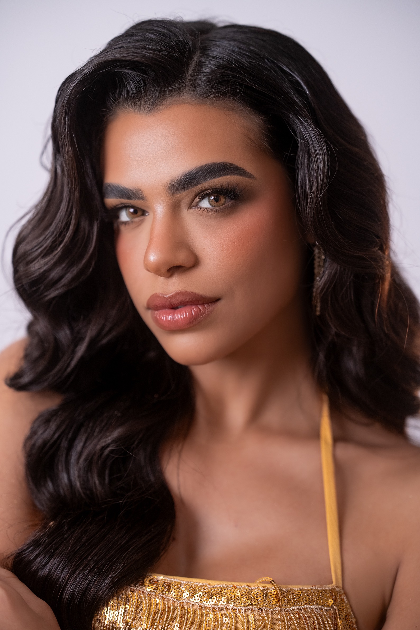 Retrato de Joandra Nashelle Miranda Sánchez, concursante número 31 de Miss Nova Fémina, con elegante vestido dorado.