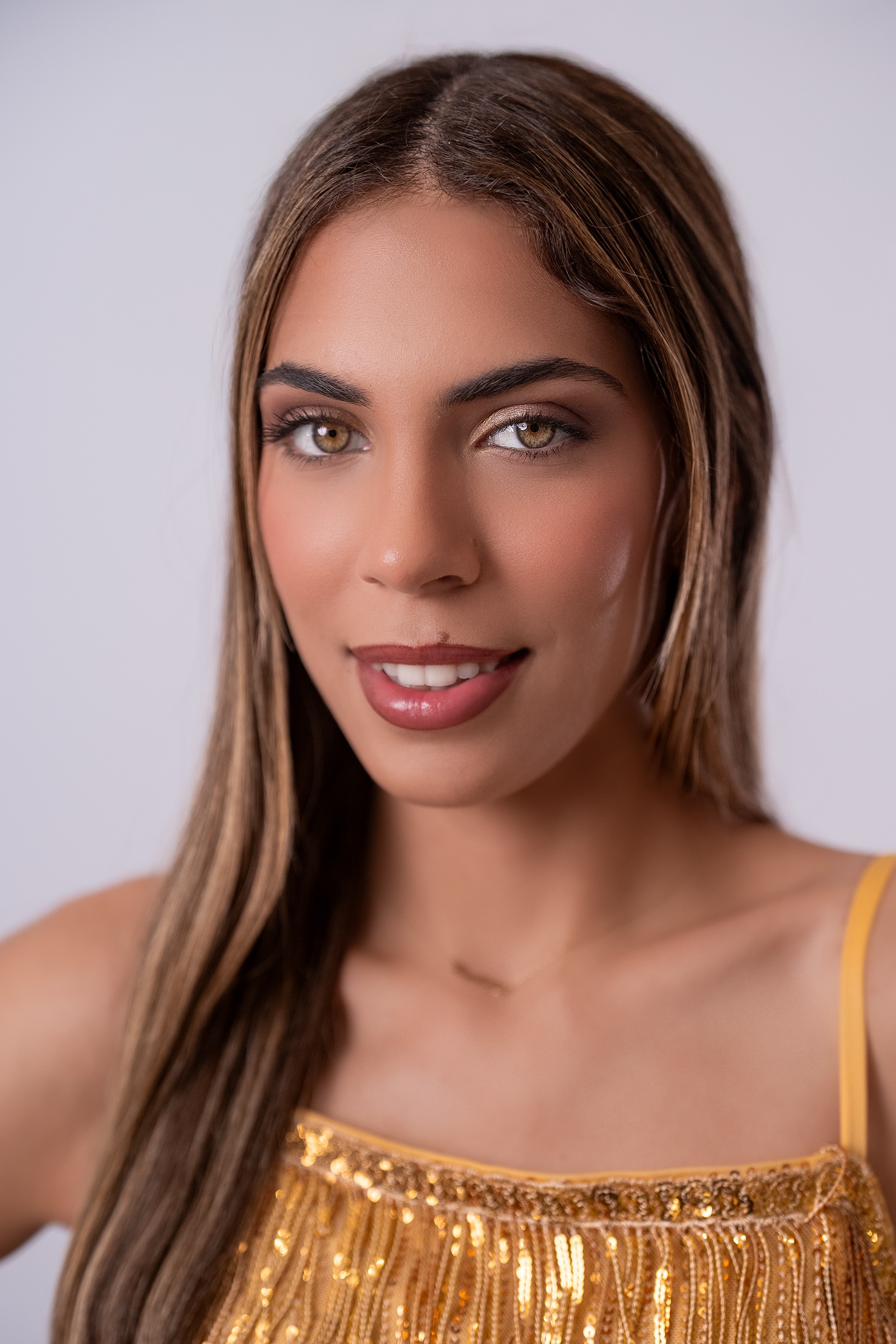 Retrato de Daniela Calero, concursante número 39 de Miss Nova Fémina, con elegante vestido dorado.