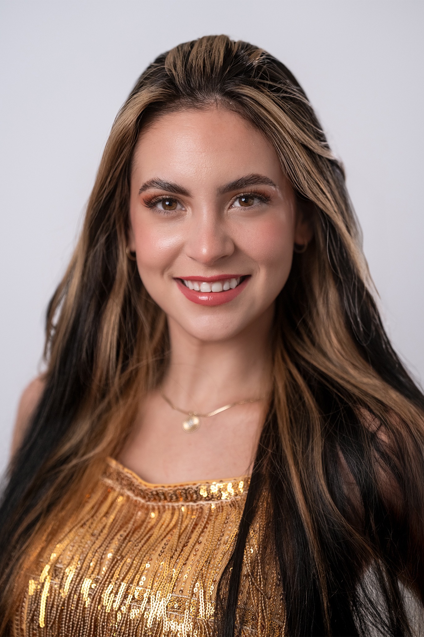 Retrato de Daniela Arencibia Pujol, concursante número 4 de Miss Nova Fémina, luciendo un vestido dorado con una sonrisa elegante.