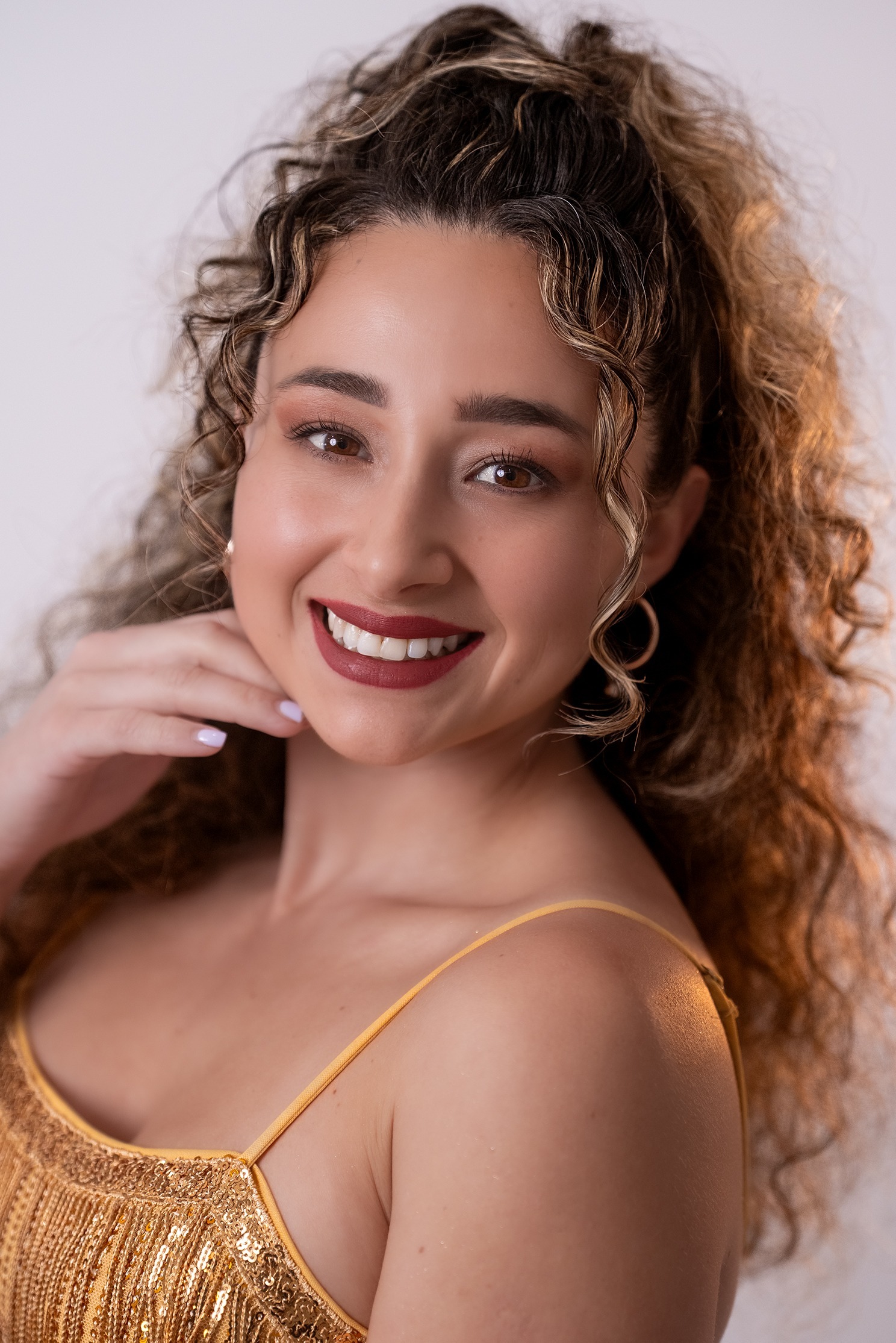 Retrato de María Belén Pastenes Atenas, concursante número 42 de Miss Nova Fémina, con vestido dorado elegante.